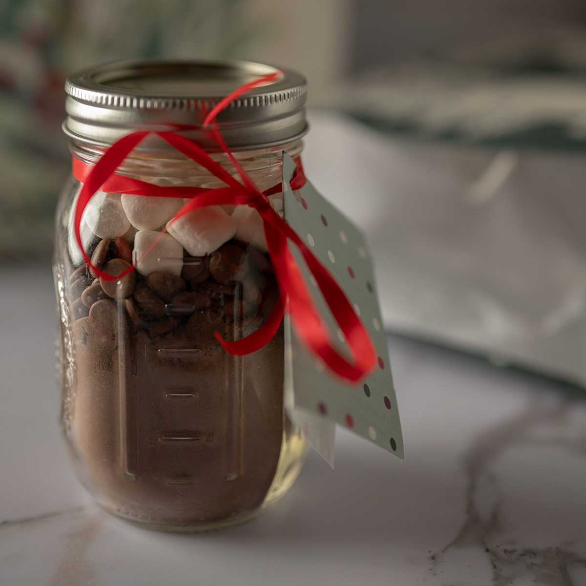 A jar of homemade hot cocoa mix tied with a red ribbon.