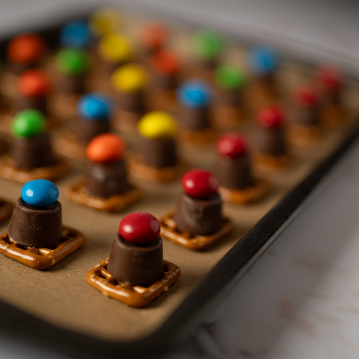 Chocolate peanut butter pretzel bites on a baking sheet.