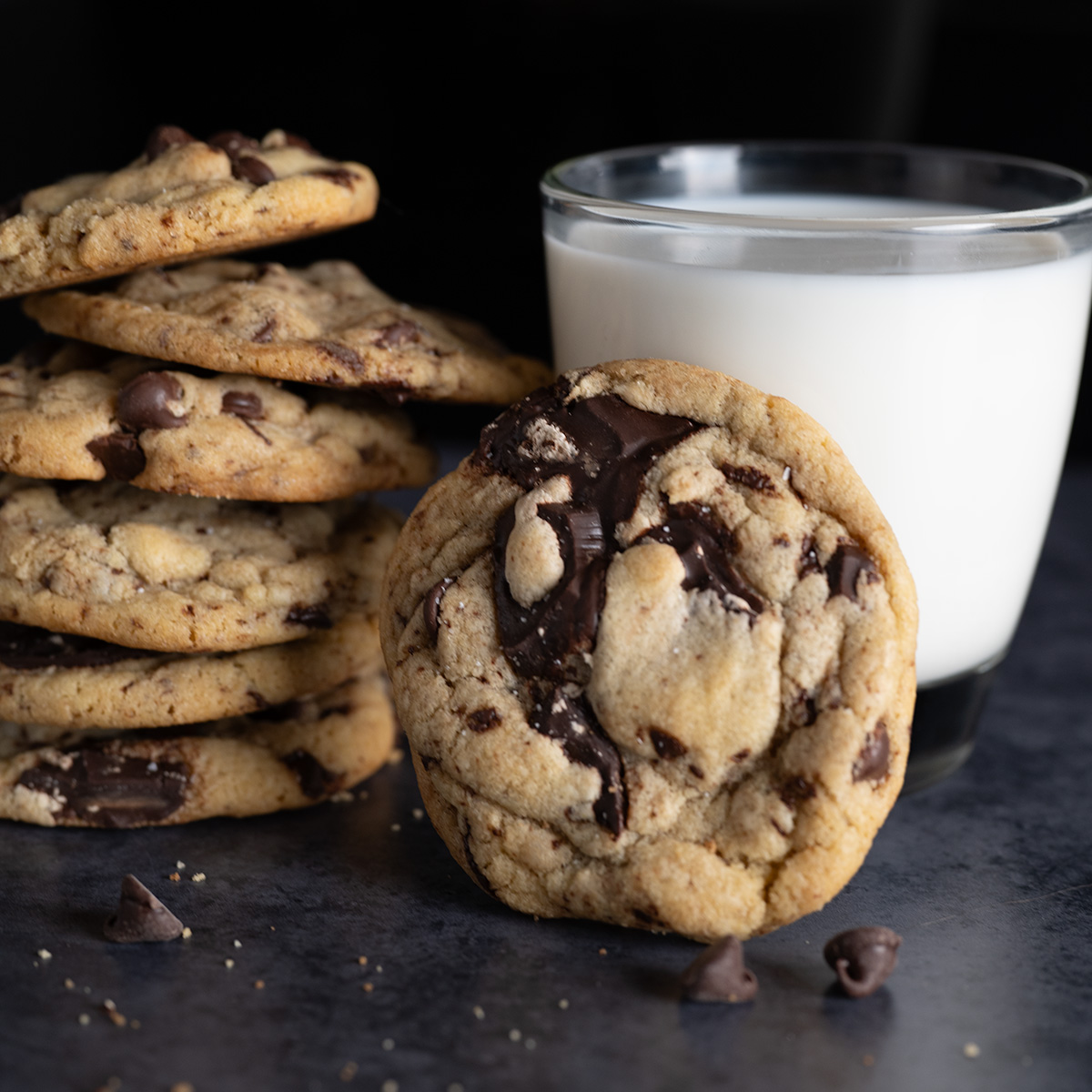 A chocolate chip cookie propped against a cold glass of milk.