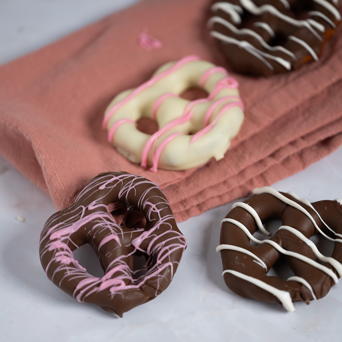Milk and white chocolate pretzels on a pink napkin.
