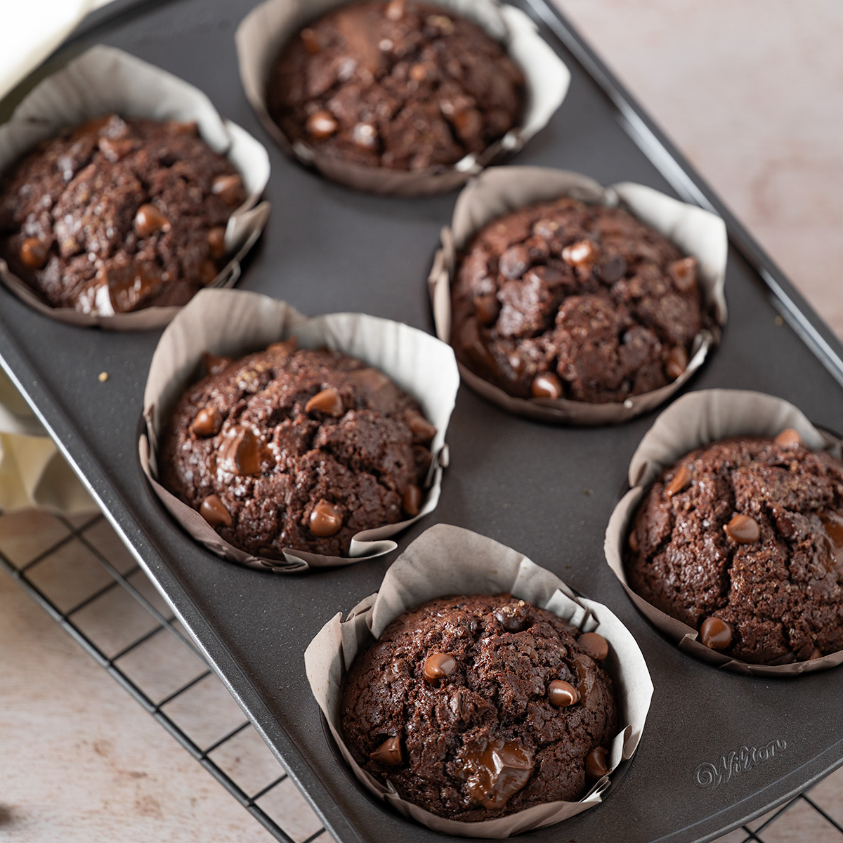 Six double chocolate muffins in a muffin tin.